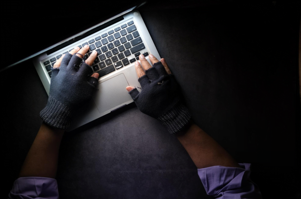 Hands wearing gloves typing on laptop illustrating cybersecurity vulnerabilities in autonomous vehicles
