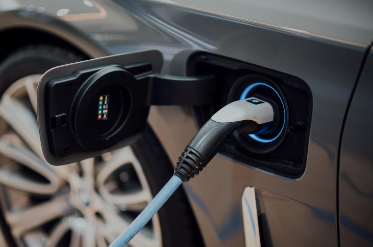 Electric vehicle charging cable connected to car, illustrating fuel efficiency and dual-fueled autonomous vehicles.