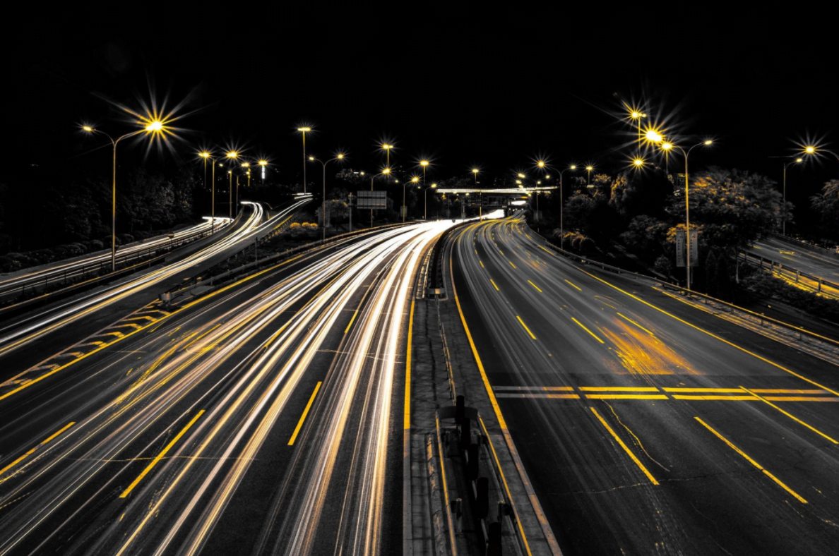 Night highway with light trails illustrating autonomous vehicle safety and driver distraction reduction.